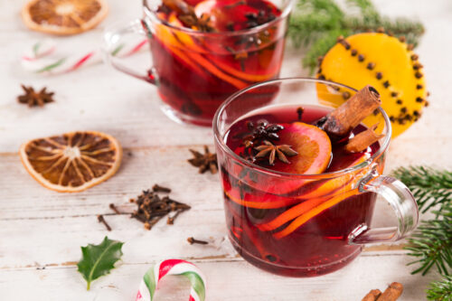 christmas hot mulled wine with various spices on old wooden background.